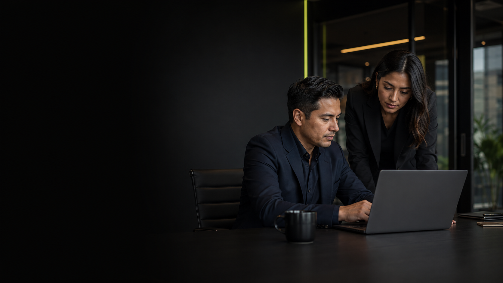 Dos profesionales revisando información en una laptop dentro de una oficina corporativa